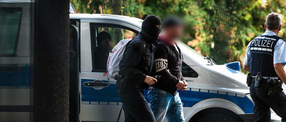 Einer der mutmaßlichen Rechtsterroristen, die in Bayern und Sachsen festgenommen wurden, erreicht den Bundesgerichtshof und wird von Polizisten abgeführt.