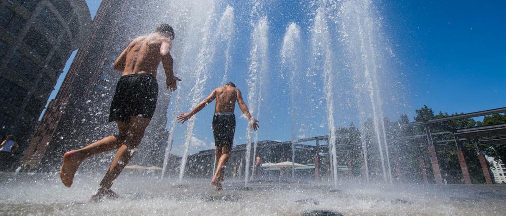 Jungen Menschen erfrischen sich am Fontänenbrunnen auf dem Walther-von-Cronberg-Platz in Frankfurt/ Main. 