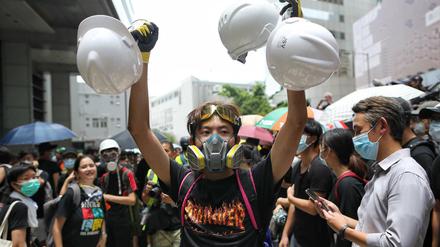 Hongkong: Ein Demonstrant mit einer Gasmaske verteilt Schutzhelme an andere Demonstranten. 