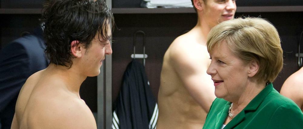 Fußballfans unter sich. Bundeskanzlerin Angela Merkel gratuliert Mesut Özil nach dem EM-Qualifikationsspiel Deutschland gegen Türkei in der Mannschaftskabine.