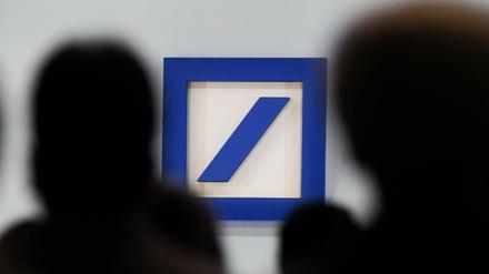 Aktionäre sitzen während der Hauptversammlung der Deutschen Bank in der Frankfurter Festhalle vor dem Unternehmenslogo. 