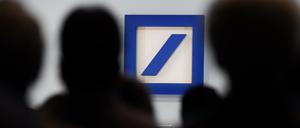 Aktionäre sitzen während der Hauptversammlung der Deutschen Bank in der Frankfurter Festhalle vor dem Unternehmenslogo.