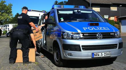 Polizisten tragen mehrere Kisten aus dem Haus des Tatverdächtigen. 