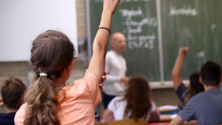 Eine Schülerin der fünften Klasse hebt im Unterricht den Finger.