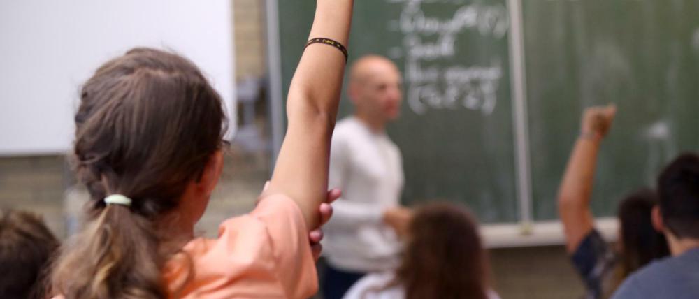 Eine Schülerin der fünften Klasse hebt im Unterricht den Finger.