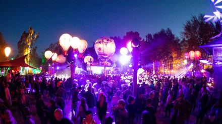 Festivalbesucher tanzen auf einer mit leuchtenden Ballonen geschmückten Bühne auf dem Gelände des Fusion-Festival 2019. 