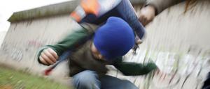 Ein Schüler drückt auf dem Schulhof eines Gymnasiums einen anderen Schüler zu Boden (gestelltes Illustrationsfoto).