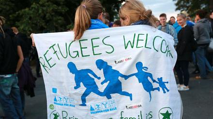 In ein Tuch gehüllt mit der Aufschrift "Refugees welcome" stehen Flüchtlingsunterstützer im Herbst 2015 in Dresden in der Nähe einer Asylbewerberunterkunft. 