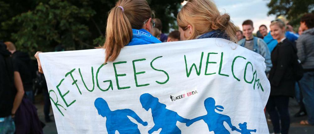In ein Tuch gehüllt mit der Aufschrift "Refugees welcome" stehen Flüchtlingsunterstützer im Herbst 2015 in Dresden in der Nähe einer Asylbewerberunterkunft.