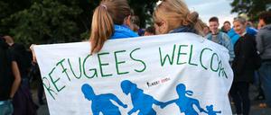 In ein Tuch gehüllt mit der Aufschrift "Refugees welcome" stehen Flüchtlingsunterstützer im Herbst 2015 in Dresden in der Nähe einer Asylbewerberunterkunft. 