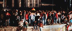 Jubelnde Menschen stehen am 9. November 1989 auf der Mauer vor dem Brandenburger Tor. 