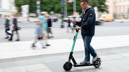 Ein Tourist fährt auf einem E-Roller durch Berlin-Mitte.