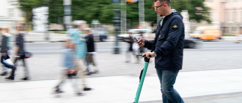 Ein Tourist fährt auf einem E-Roller durch Berlin-Mitte.