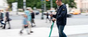 Ein Tourist fährt auf einem E-Roller durch Berlin-Mitte.