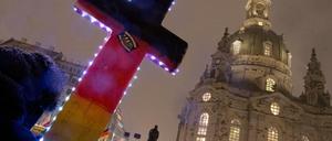 Anhänger der fremden - und islamfeindlichen Pegida-Bewegung demonstrieren im Februar 2016 mit einem beleuchteten Kreuz vor der Frauenkirche in Dresden (Sachsen).