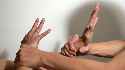 Die Arme eines Mannes halten mit Gewalt die Arme einer Frau fest.