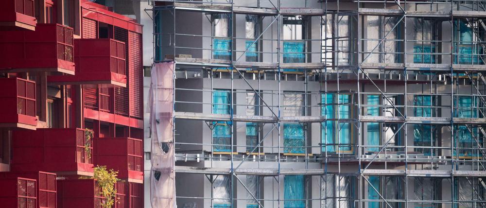  Ein Baugerüst steht an einem Rohbau neben bereits fertiggestellten Neubau-Wohnungen in Kreuzberg.