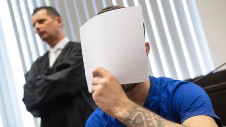Mit einem Zettel verdeckt der Angeklagte Ali B. beim Betreten des Gerichtssaals sein Gesicht vor den Kameras der Journalisten.