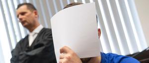 Mit einem Zettel verdeckt der Angeklagte Ali B. beim Betreten des Gerichtssaals sein Gesicht vor den Kameras der Journalisten.