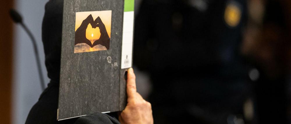 Der 58-jährige Angeklagte hält im Gerichtssaal einen Aktenordner mit einem Herz aus zwei Händen vor sein Gesicht