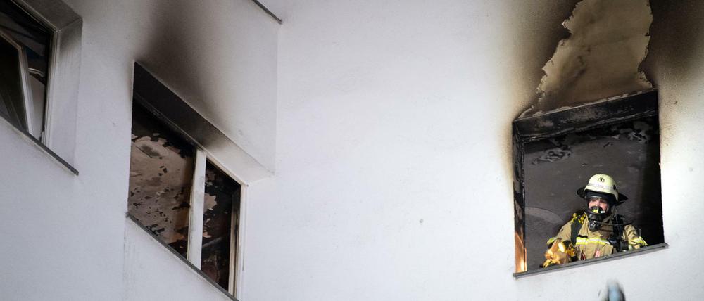 Tatort Gropiusstadt. Ein Feuerwehrmann wirft verbrannte Gegenstände aus dem Fenster der ausgebrannten Wohnung.