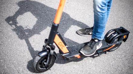 Ein Mann steht auf einem E-Tretroller.