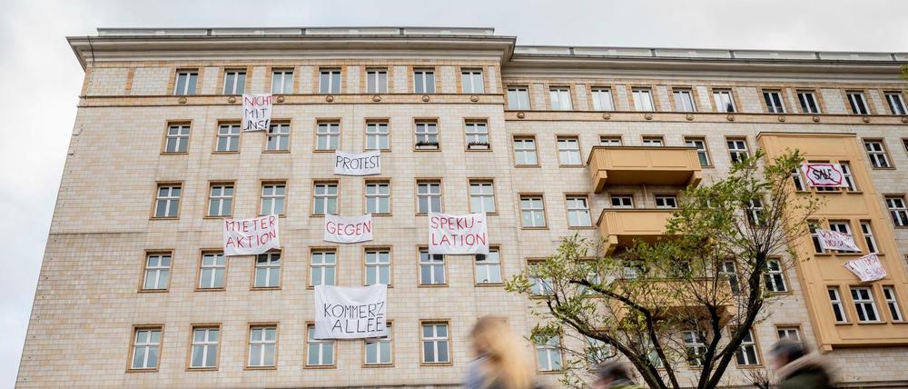 Plakate gegen den Verkauf von Mietwohnungen an die Deutsche Wohnen hängen an einer Gebäudefassade in der Karl-Marx-Allee.