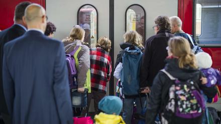 Reisende warten Bahnhof vor der Tür eines Regionalzuges.