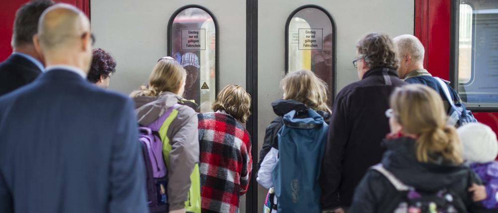 Reisende warten Bahnhof vor der Tür eines Regionalzuges.