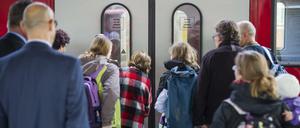 Reisende warten Bahnhof vor der Tür eines Regionalzuges.