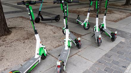Mehrere E-Tretroller stehen unter Bäumen in Berlin.
