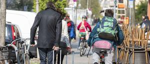 Fahrradfahrer und Fußgänger auf einem engen Bürgersteig in Berlin.