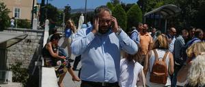 Angestellte greifen nach einem starken Erdbeben in Athen zum Handy. 