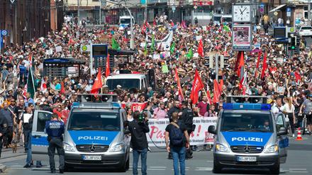 Teilnehmer einer Gegendemonstration gehen mit Plakaten und Flaggen durch Kassel