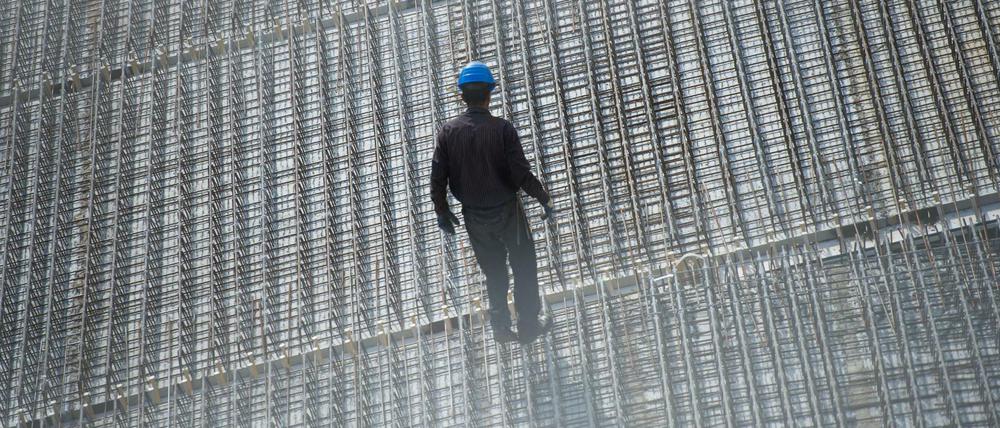 Ein Arbeiter steht auf einer Baustelle im Berliner Hansaviertel. Die Auftragsbücher der Bauunternehmen sind prall gefüllt. Doch auch im Bauhandwerk fehlen zunehmend Fachkräfte.