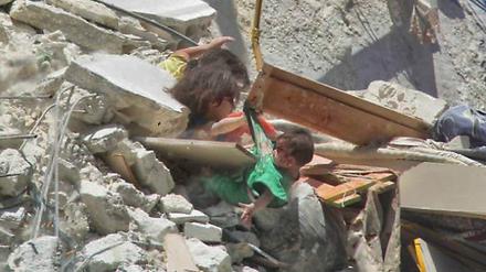 Ein sieben Monate altes Mädchen droht nach einem Luftangriff in Syrien in die Tiefe zu stürzen. Seine Schwestern halten es fest.