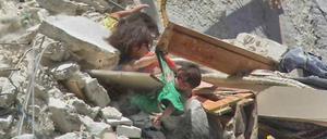 Ein sieben Monate altes Mädchen droht nach einem Luftangriff in Syrien in die Tiefe zu stürzen. Seine Schwestern halten es fest.