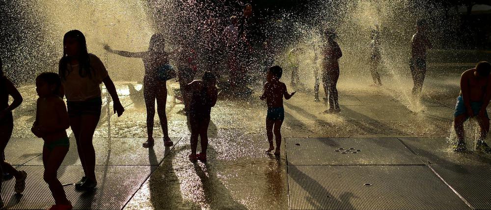 Spanien, Pamplona: Menschen kühlen sich in einem Brunnen ab, als die Sonne an einem heißen Sommertag untergeht.