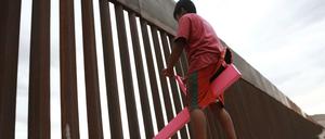 Mexiko, Ciudad Juarez: Ein Kind sitzt auf einer Wippe, die am Grenzzaun zwischen Mexiko und den USA angebracht ist.