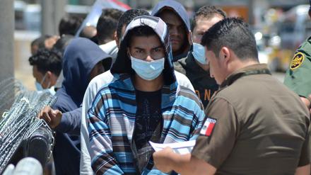 Die Dokumente einer Gruppe von Migranten werden auf mexikanischer Seite an der Grenze überprüft. 