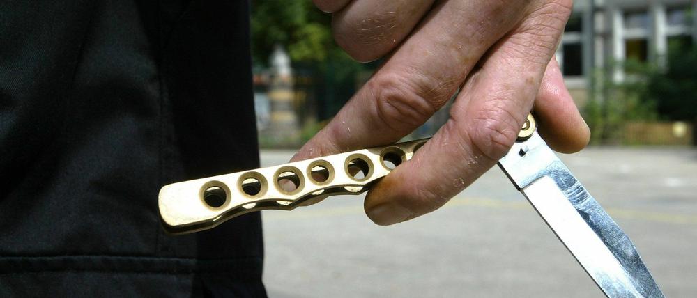 Straftäter hält ein Butterflymesser in der Hand (Symbolbild).