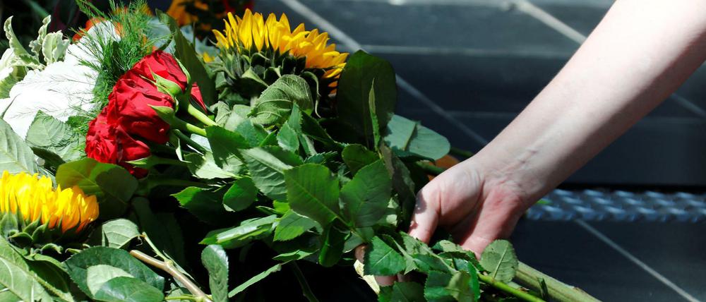 Eine Frau legt auf dem Hauptbahnhof Frankfurt am Main Blumen nieder.