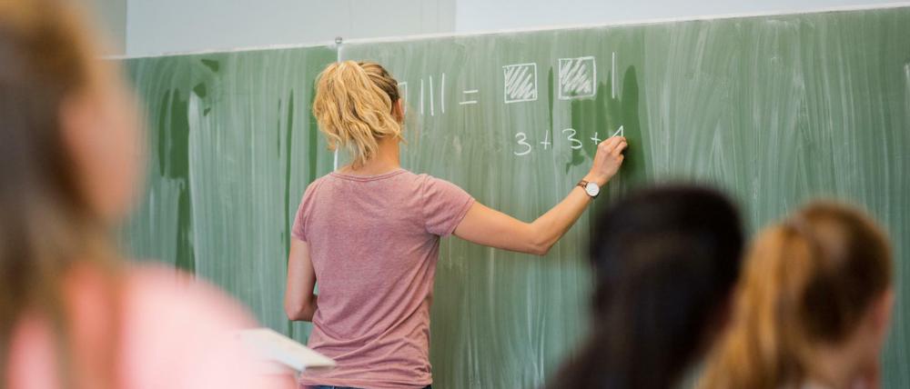 Eine Lehrerin schreibt an eine Schultafel im Mathematikunterricht einer achten Klasse an einer Integrierten Gesamtschule.