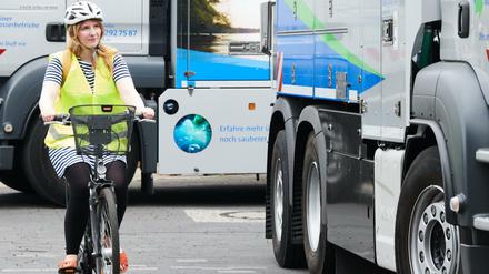 Eine Mitarbeiterin der Wasserbetriebe fährt als Testperson mit ihrem Fahrrad neben einem Lkw der Berliner Wasserbetriebe, der mit Abbiegeassistenten nachgerüstet wurde.