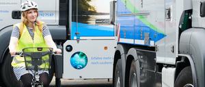 Eine Mitarbeiterin der Wasserbetriebe fährt als Testperson mit ihrem Fahrrad neben einem Lkw der Berliner Wasserbetriebe, der mit Abbiegeassistenten nachgerüstet wurde.