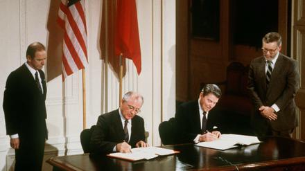 Der damalige sowjetische Parteichef Michail Gorbatschow (l) und der damalige US-Präsident Ronald Reagan unterzeichnen den INF-Vertrag zur Vernichtung der atomaren Mittelstreckenraketen.