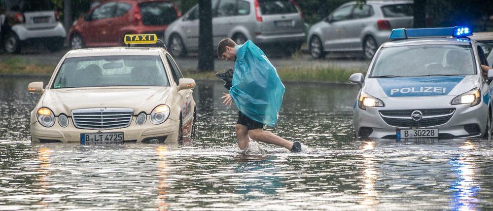 Ein Mann geht über die überflutete Tiergartenstraße in Berlin Mitte. Mehrere Autos blieben im teilweise Knietiefen Wasser liegen.