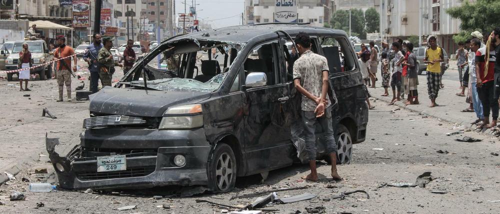 Ein Junge schaut sich ein schwer beschädigtes Auto nach einem Autobombenanschlag neben einer dadurch zerstörten Polizeistation an.