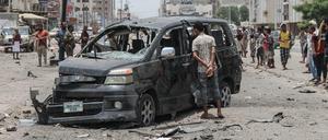 Ein Junge schaut sich ein schwer beschädigtes Auto nach einem Autobombenanschlag neben einer dadurch zerstörten Polizeistation an. 