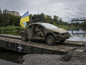 Ukrainische Fallschirmjäger fahren in einem Fahrzeug mit ukrainischer Fahne auf der Pantone-Brücke über den Fluss Siverskiy-Donets im kürzlich zurückeroberten Gebiet von Isjum. 